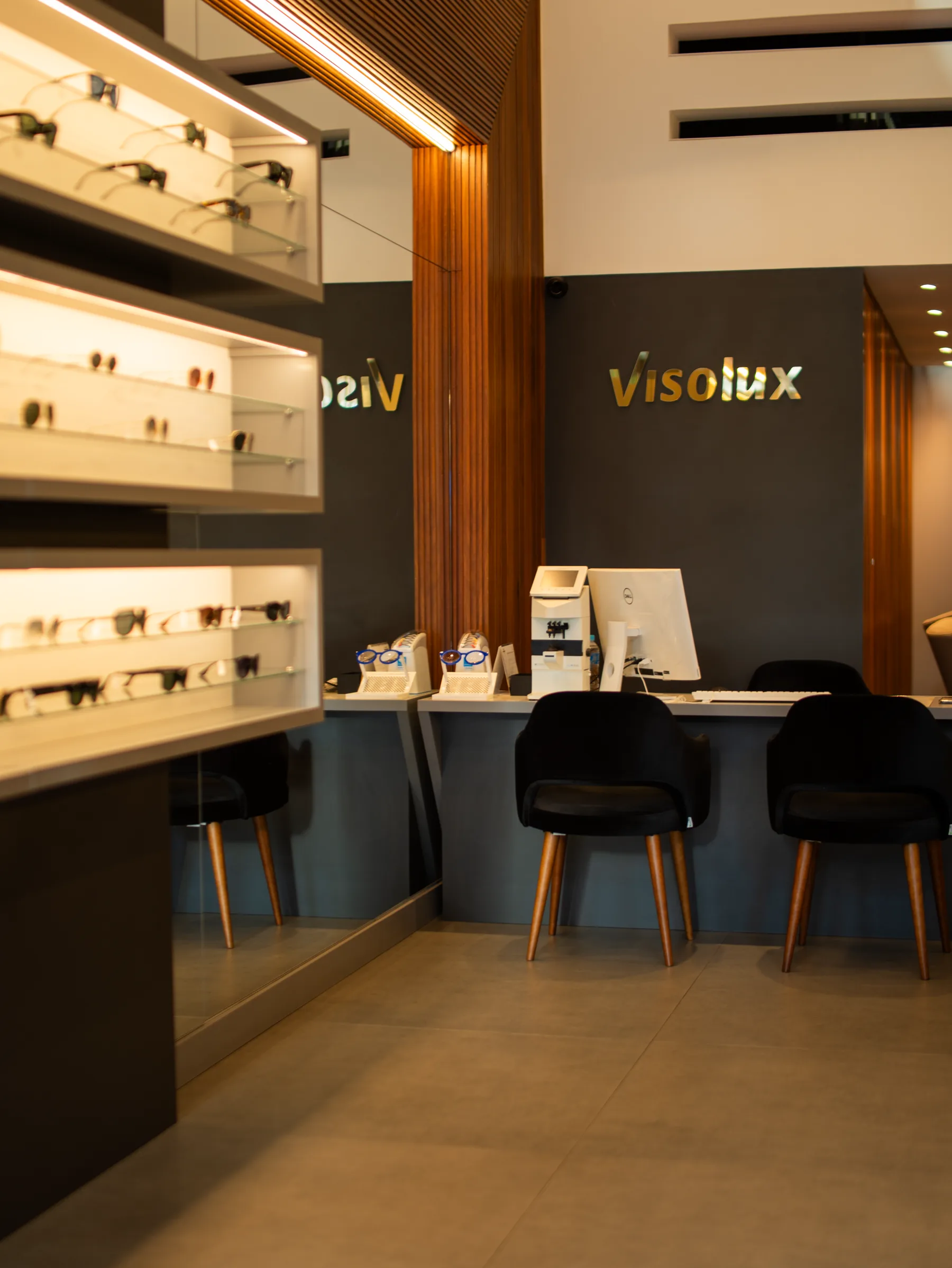 Área de atendimento da Visolux com logo, madeira e expositores iluminados